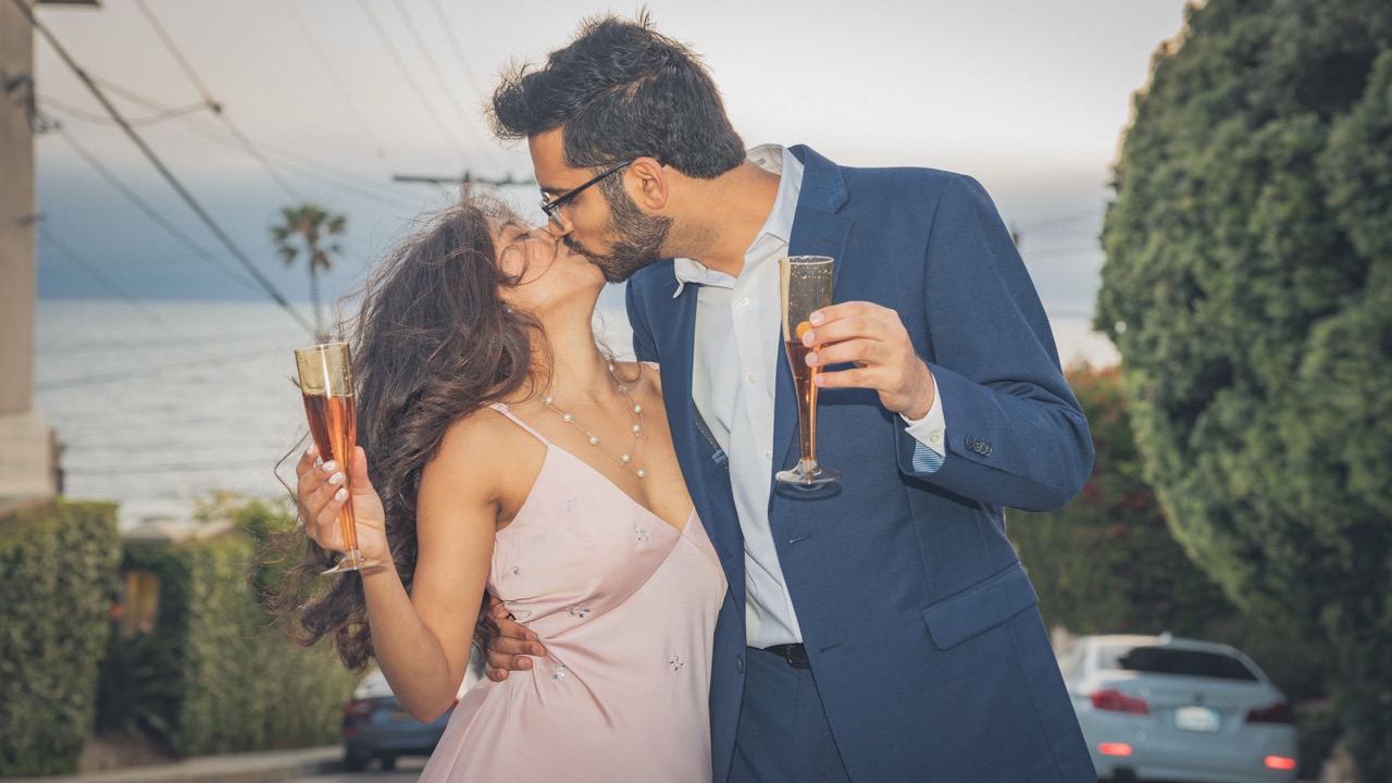An engaged couple kissing and raising champagne glasses