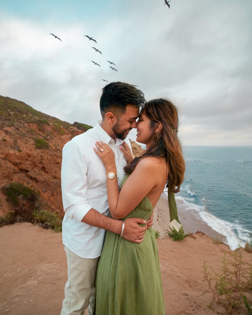 An engaged couple embracing on a coastal overlook